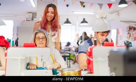 Teacher helping adult student sewing during creative workshop Stock Photo