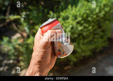 Hand Crushing an aluminum can. finished beverage to be recycled. Stock Photo