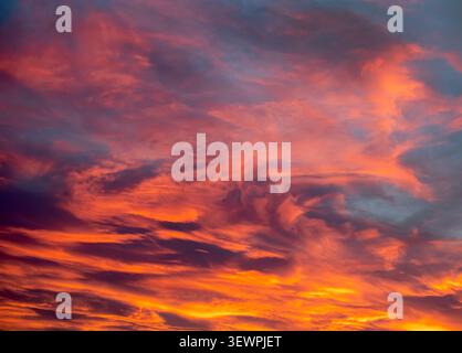 Sunset paints drifting clouds in glowing shades of pink purple and gold across the evening sky Stock Photo