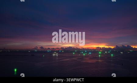 A vibrant twilight seascape featuring numerous fishing vessels with glowing green navigation lights across the horizon in chon buri thailand. Stock Photo