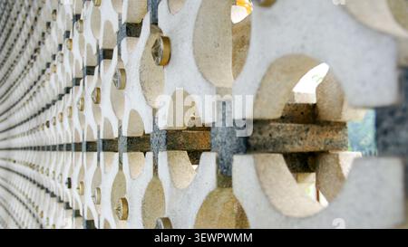 A perspective of a modern breeze block wall panel featuring traditional Islamic star-like ventilation patterns and small brass studs, blurring smoothl Stock Photo