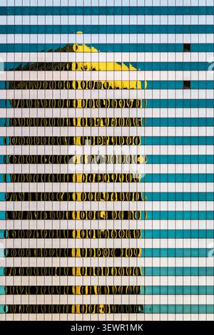 Reflection of a city skyscraper in the windows of a corporate office building. Modern office building exterior featuring blue stripes and golden refle Stock Photo