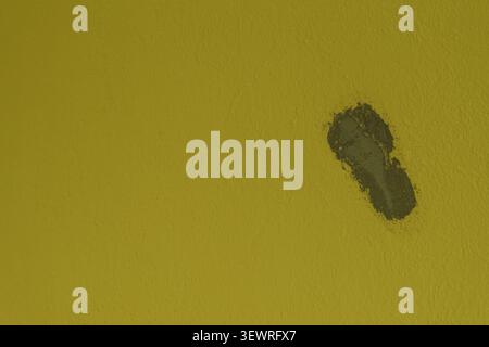 Yellow painted textured wall surface revealing a chipped and damaged area, exposing the rough grey plaster layer underneath and creating a contrasting Stock Photo