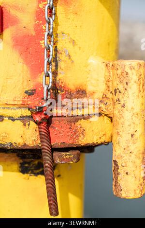 Industrial detail of rusty metal chain and bolt on yellow surface Stock Photo