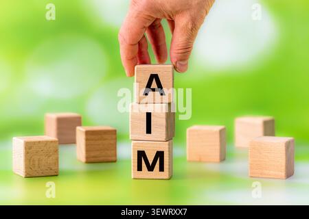 AIM Concept representing business goals, corporate strategy, and mission statement. Word Aim made of wooden letter cubes on a natural green bokeh back Stock Photo