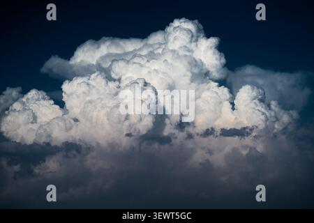 View of large white cumulus clouds against a deep blue sky over the Arashan lake area in Pop District, Namangan Region, Uzbekistan. Stock Photo