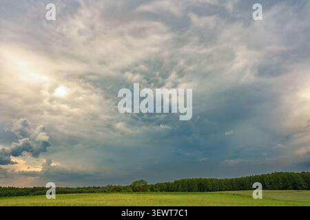Dramatic storm clouds over green countryside landscape before rain Stock Photo
