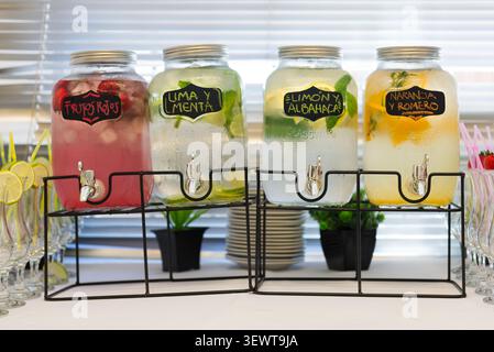 Variety of refreshing fruit-infused water and sparkling beverages in glass dispensers at an event Stock Photo