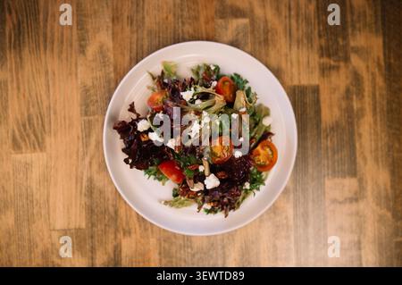white plate filled with a salad on a wooden table Stock Photo