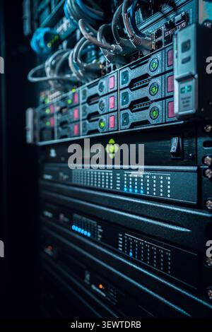 View of a server rack with blinking status lights, network cables, and hardware components in a data center in Los Angeles, California, United States. Stock Photo