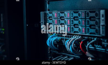View of a server rack with organized blue and red ethernet cables connected to networking hardware in a data center in Los Angeles, California, United Stock Photo