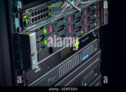 View of a server rack with networking equipment, blinking green status lights, and storage drives in Los Angeles, California, United States. Stock Photo