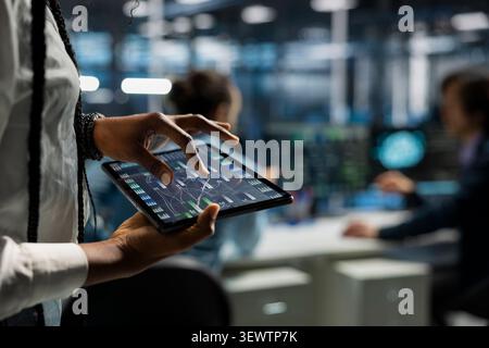 Data center programmer uses a digital tablet in a data center to manage AI systems and optimize server infrastructure. Stock Photo