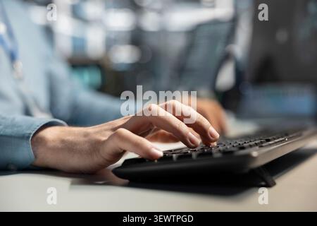 Data center technician uses a desktop computer in a data center to run hardware diagnostics and maintain operational stability. Stock Photo
