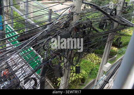 Messy tangled overhead power lines and electricity cables on a street pole in Bangkok, Thailand, 31 January, 2025 Stock Photo
