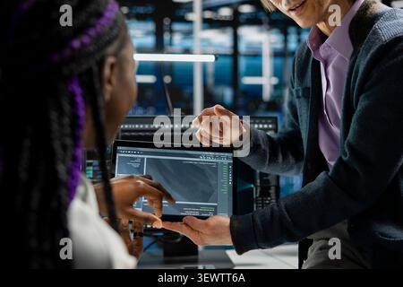 Data center programmers use a digital tablet in a data center to support automation monitoring and reliable server workflows. Stock Photo
