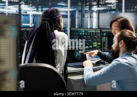 Data center team reviews performance analytics on a computer in a data center to optimize storage systems and resource use. Stock Photo