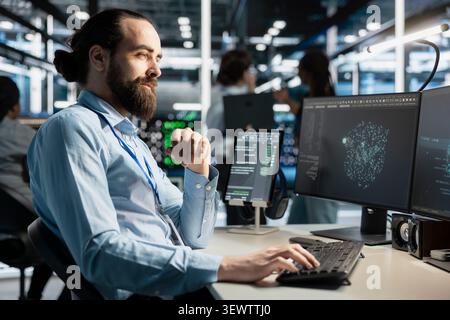 Data center technician uses a computer to run diagnostics, update servers and check infrastructure performance. Stock Photo