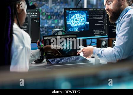 Data center colleagues collaborate on coding and AI automation scripts while reviewing server infrastructure together. Stock Photo