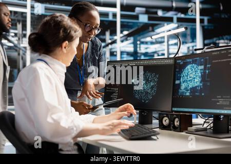 System administrators use a computer in a server hub to visualize AI neural networks and brainstorm system oversight. Stock Photo