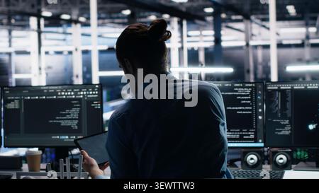 Administrator programs on a laptop in a data center with generative AI assistance. Stock Photo