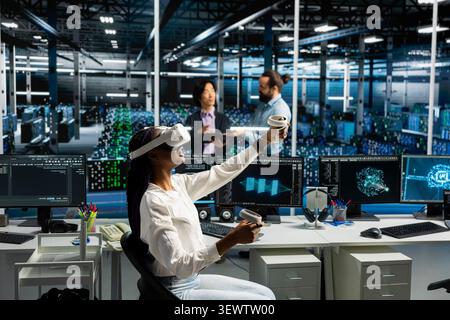 Administrator wears a headset in a server hub, using artificial intelligence troubleshooting to assist users. Stock Photo