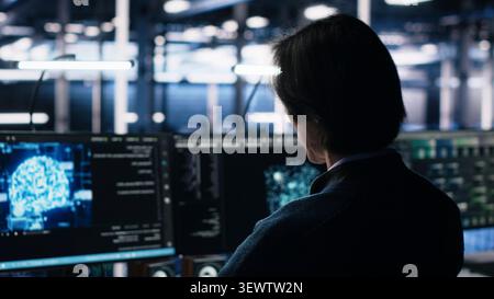 System administrator reviews artificial intelligence systems and machine learning processes inside a data center. Stock Photo