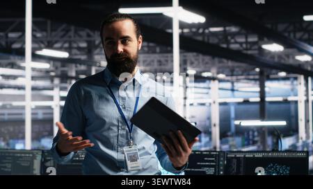 Data center lead programmer presents AI server technology during a filmed tour of high-tech infrastructure. Stock Photo