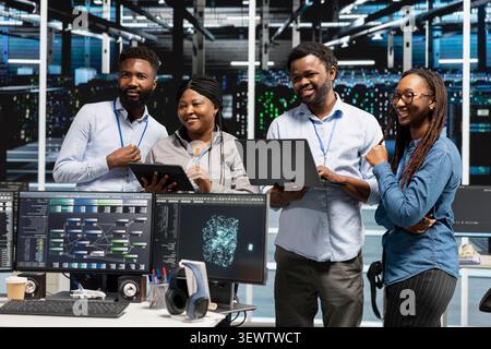 Cheerful high tech server room specialists collaborating, working with deep learning algorithms. Stock Photo