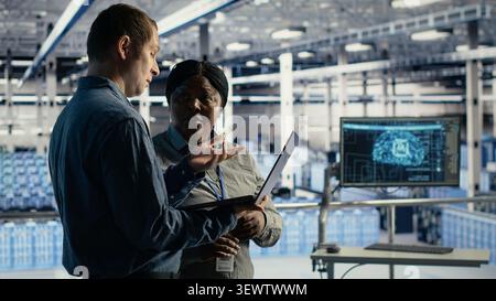 Data center engineering team uses deep learning tools on a digital device in a server room to improve AI operations and system efficiency. Stock Photo