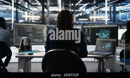 Irritated high tech server room technical specialist punching desk, irked by glitches. Stock Photo