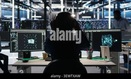 High tech server room technical specialist implements AI virtualization frameworks to enhance server clusters, while IT professional doing AI predictive analysis. Stock Photo