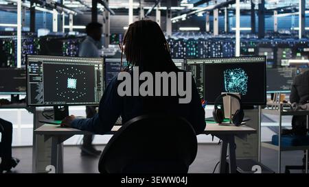 Server room software programmer interpreting AI generated data analytics graphs, wearing headphones, while operates AI tool showing system metrics, listening music. Stock Photo