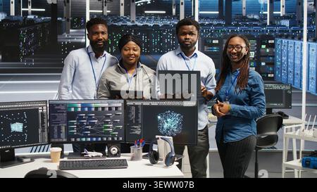 Friendly high tech server room technicians assessing digital infrastructure issues. Stock Photo