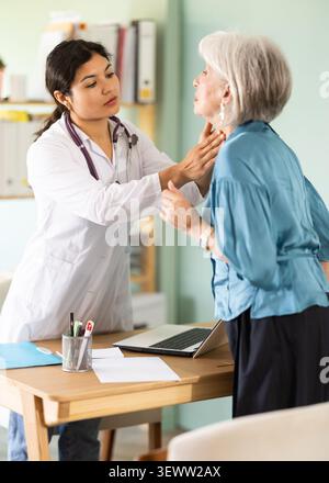 Female doctor examining elderly woman's throat Stock Photo