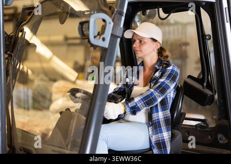 Woman driving fork lift in storehouse Stock Photo