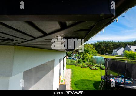Black security dome camera observing a house backyard and surroundings from under the eaves Stock Photo