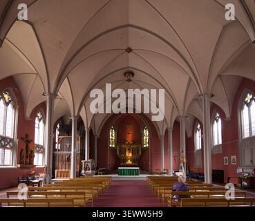 A visitor finds a moment of quiet reflection inside the historic St Mary’s Church in Somers Town, Camden, London. Stock Photo