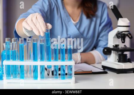Scientist handling test tubes with blue liquid in laboratory Stock Photo