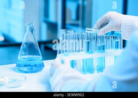 Scientist handling test tubes with blue liquid in laboratory Stock Photo