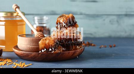 Honeycomb pieces with honey jar and dipper on wooden table Stock Photo