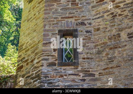 Medieval castle window stone wall, ancient gothic fortress tower facade with narrow diamond pane window and weathered historic masonry close up Stock Photo
