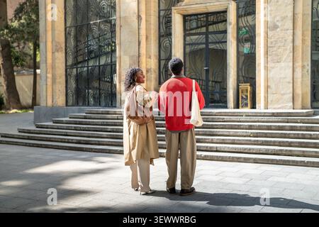 Cheerful african american couple man and woman strolling together through city on warm sunny day. Stock Photo
