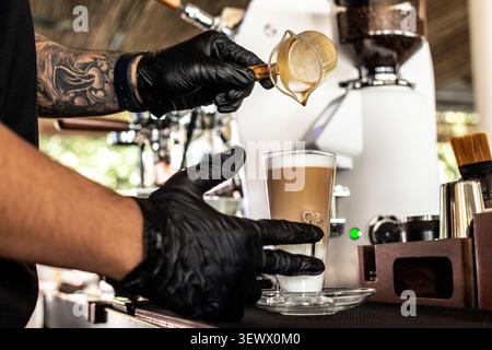 Barista at premium coffee shop making a Latte with professional equipment at cafe in Italy Stock Photo