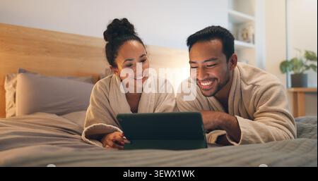 Happy couple, online and relax with tablet on bed, entertainment or streaming film with subscription. Watching, movie and people with technology Stock Photo