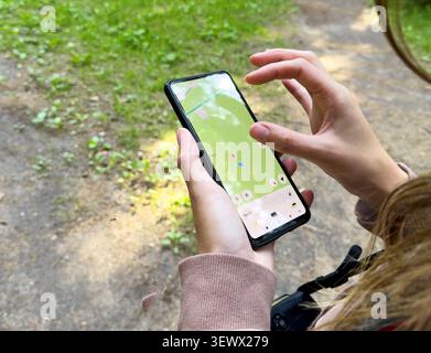 Hands use smartphone map application in outdoor setting. Person navigates forest using digital interface on screen. Technology concept reflects naviga Stock Photo