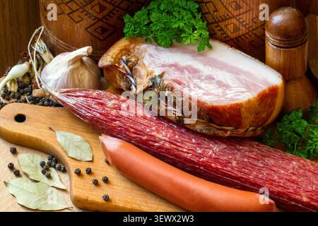 Sausage, lard and meat products. Sausages on a wooden cutting board. Composition with spices and herbs. Stock Photo