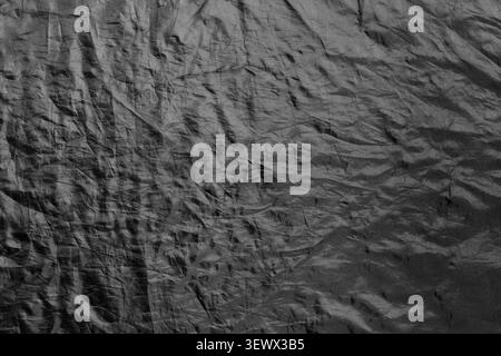 Dark textured surface with wrinkled material forming abstract background. Close composition showing rough pattern and minimal design. Concept of textu Stock Photo