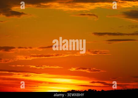 Vibrant orange sky. Dramatic partly cloudy sunset sky background Stock Photo