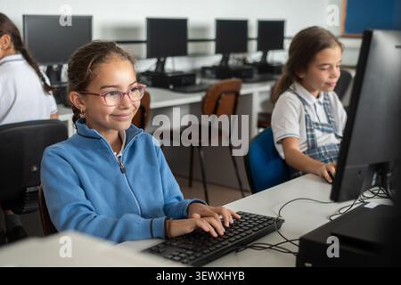 Smiling Elementary School Girl Using Desktop Computer in Computer Lab Stock Photo